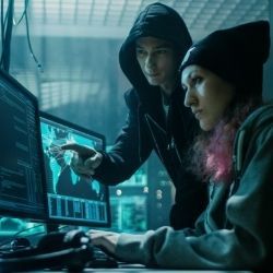 男性和女性黑客在计算机上工作以执行恶意行为的照片