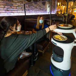 在迈阿密的一家Sergios餐厅，一台Servi机器人给顾客送来食物。