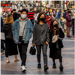 戴面具的夫妇和一个年轻女孩走在拥挤的街道上