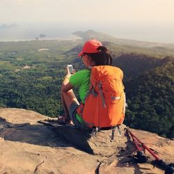 在山顶上使用智能手机俯瞰风景的人。