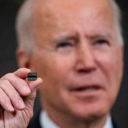 约瑟夫·拜登总统用两个手指夹着一个微芯片。