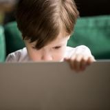 一个孩子在看笔记本电脑屏幕。